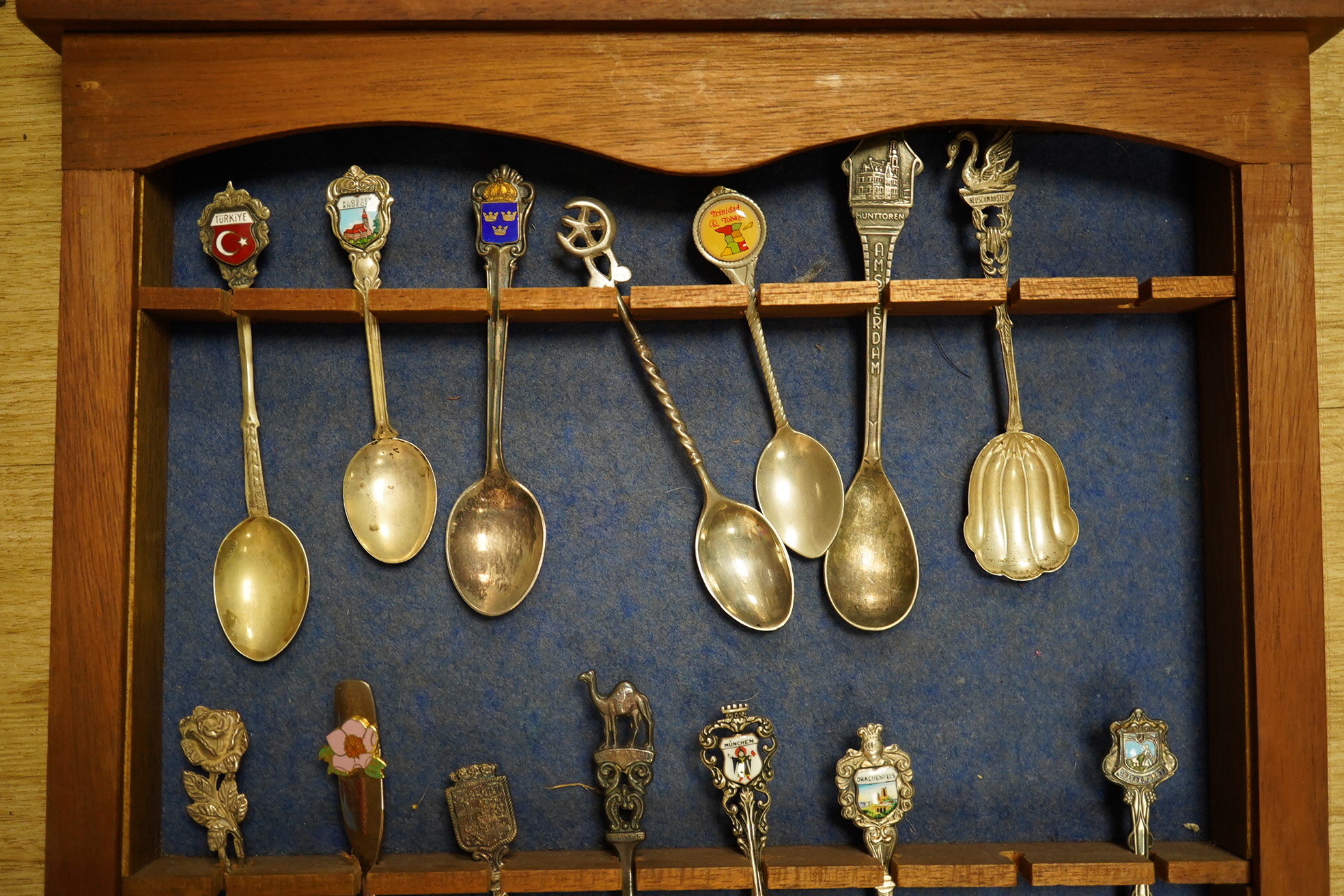 A quantity of collectors spoons from various countries, some silver with enamel, housed in a cabinet. Condition - fair